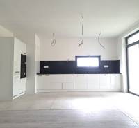 Kuchyně v rodinném domě s podlahou s dřevěným dekorem, bílými skříňkami a vestavěnými spotřebiči.