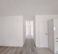 Světlý interiér rodinného domu s podlahou s dřevěným dekorem a bílými stěnami.