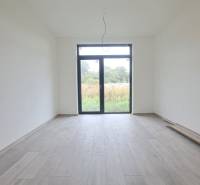 Interiér rodinného domu s podlahou s dřevěným dekorem a velkým oknem.