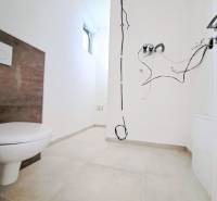 Koupelna v rodinném domě s volnými kabely a záchodem, bez doplňků.