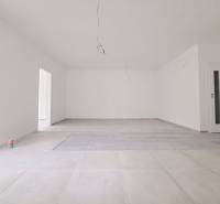 Prostorná místnost s podlahou s dřevěným dekorem a bílými stěnami v rodinném domě.