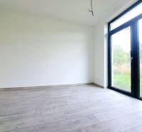 Prázdná místnost s velkým oknem a podlahou s dřevěným dekorem v rodinném domě.