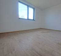 Prostorná místnost s podlahou s dřevěným dekorem a velkým oknem v rodinném domě.