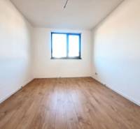 Výhled na pokoj s bílými stěnami a podlahou s dřevěným dekorem v rodinném domě.