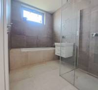 Koupelna v rodinném domě s vanou, sprchovým koutem a umyvadlem.