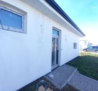 Rodinný dům v Galantě, s bílou fasádou a zámkovou dlažbou na předzahrádce.