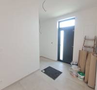 Vstupní hala rodinného domu s dlažbou, vedle dveří je schůdek a materiál.