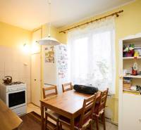 Kuchyně v 3-pokojovém bytě se stolem, židlemi a kuchyňskou linkou.