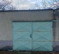 Garážová vrata se světle modrými dveřmi a opadané listí v Selicích.