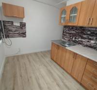 Kuchyně v 3pokojovém bytě má dřevěný dekor podlahy a jednoduché skříňky.