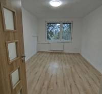 Prostorný pokoj v 3-pokojovém bytě s podlahou s dřevěným dekorem a velkým oknem.