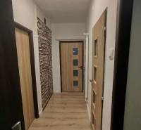 Chodba se světlou podlahou a dřevěnými dveřmi v 3-pokojovém bytě.