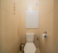 Toaleta s béžovými obklady v 2-pokojovém bytě.