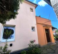 Rodinný dům v Partizánském má růžovou fasádu, malá okénka a vchodové dveře.