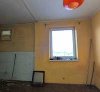 Pokoj v rodinném domě s oknem, koštětem a oranžovým osvětlením.