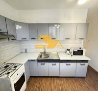 Kuchyně ve 3-pokojovém bytě s podlahou s dřevěným dekorem a moderním vybavením.