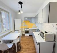 Kuchyně ve 3-pokojovém bytě s bílými skříňkami a podlahou s dřevěným dekorem.