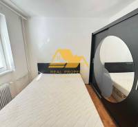 Ložnice v 3-pokojovém bytě s postelí, skříní a podlahou s dřevěným dekorem.