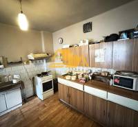 Kuchyně v rodinném domě s dřevěným dekorem podlahy, kuchyňská linka, spotřebiče, úložné skříňky.