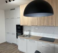 Kuchyně v 2-pokojovém bytě s podlahou s dřevěným dekorem a světlým nábytkem.