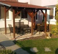 Rodinný dům v Černé Vodě s terasou, zahradním nábytkem a zeleným trávníkem.