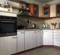 Kuchyně v rodinném domě s podlahou s dřevěným dekorem a světlými skříňkami.