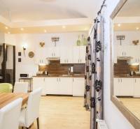 Kuchyně 2pokojového bytu s podlahou s dřevěným dekorem, bílými skříňkami a stolem.