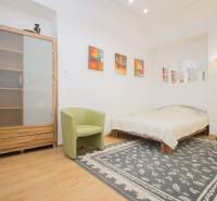 Ložnice v 2pokojovém bytě s podlahou s dřevěným dekorem, kobercem a postelí.