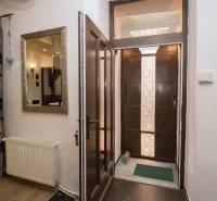 Vstupní chodba s dřevěnými dveřmi, zrcadlem a závěsy v 2-pokojovém bytě.