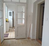 Interiér rodinného domu s bílými dveřmi a podlahou z dlaždic.