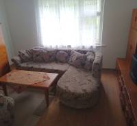 Obývací pokoj v rodinném domě s rohovou sedačkou a stolkem na podlaze s dřevěným dekorem.