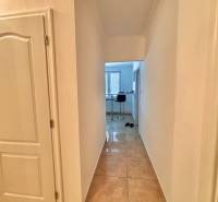 Chodba v 2-pokojovém bytě s dlažbou a otevřeným výhledem do kuchyně.