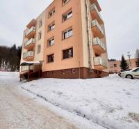 Bytový dům v zasněžené Oščadnici s 2pokojovým bytem, kolem kterého je zimní krajina.