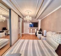 Ložnice v 2-pokojovém bytě s podlahou s dřevěným dekorem a velkou zrcadlovou skříní.