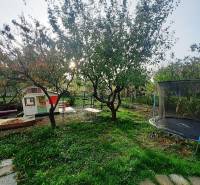 Zahrada u chaty v Pozdišovcích s domečkem, houpačkou a trampolínou.