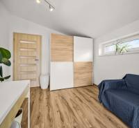 Pokoj v rodinném domě s podlahou s dřevěným dekorem, skříní a pohovkou.