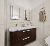 Koupelna v rodinném domě s dvojitým umyvadlem a tmavou skříňkou.