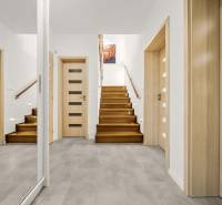 Vstupní hala v rodinném domě s podlahou s dřevěným dekorem a schodištěm.