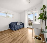 Pokoj v rodinném domě s pohovkou, okny a podlahou s dřevěným dekorem.