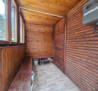 Dřevěná veranda chaty s podlahou s dřevěným dekorem a lavicí na uskladnění.