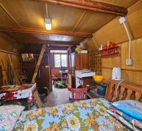 Interiér chaty s dřevěným dekorem, nábytkem a kuchyňskými potřebami.