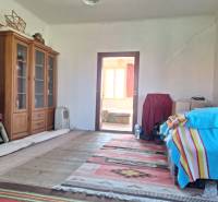 Pokoj v rodinném domě s regály na knihy, postelí s barevnou dekou a kobercem.