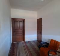 Interiér rodinného domu s dveřmi, křeslem a kobercovým běhounem.