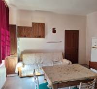 Interiér rodinného domu s pohovkou, jídelním stolem a dřevěnými skříňkami.