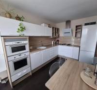Kuchyně v 3-pokojovém bytě s bílou linkou a podlahou s dřevěným dekorem.