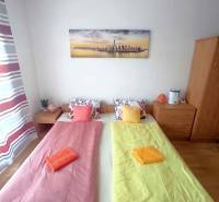 Ložnice v rekreačním apartmánu s dvěma postelemi, obrazem a pestrobarevným povlečením.