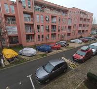 Rekreační apartmán v Burgasu se zaparkovanými auty před růžovou budovou.