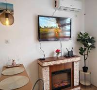 Interiér rekreačního apartmánu s krbem, televizorem a jídelním stolem.