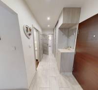 Chodba v 2-pokojovém bytě s věšákovou stěnou a bílými stěnami.