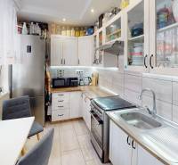 Kuchyně v 2-pokojovém bytě s bílými skříňkami a stříbrnými spotřebiči.